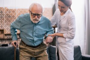 A private nurse helping elderly patient get up