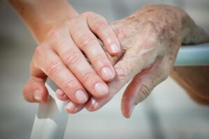 A healthcare provider holding an elderly person's hand